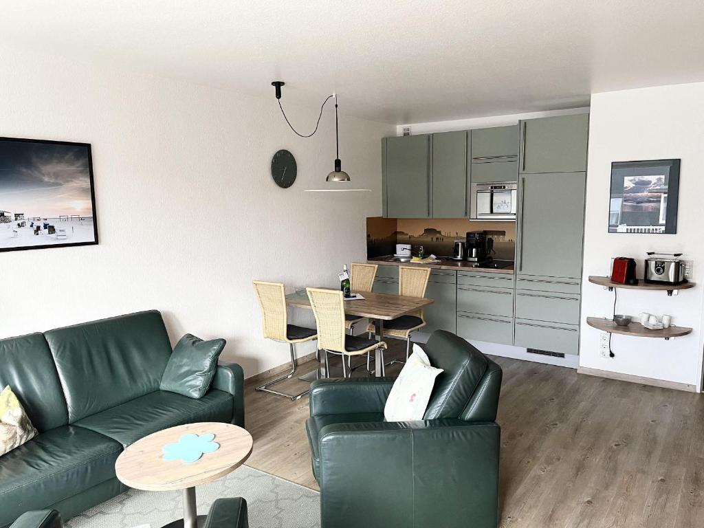 uma sala de estar com um sofá verde e uma mesa em Germania-34 em Sankt Peter-Ording