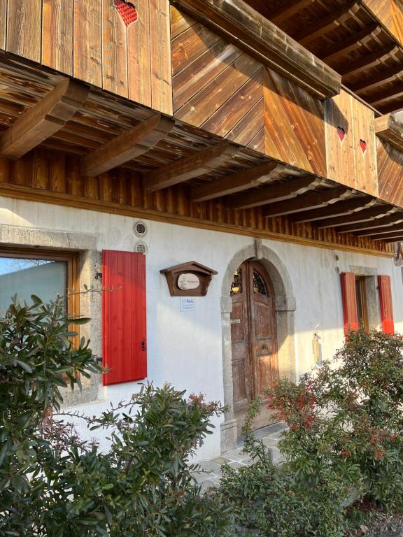 un edificio con una porta rossa e un tetto in legno di CASA VACANZE RANUNCOLO 6 a Sùtrio