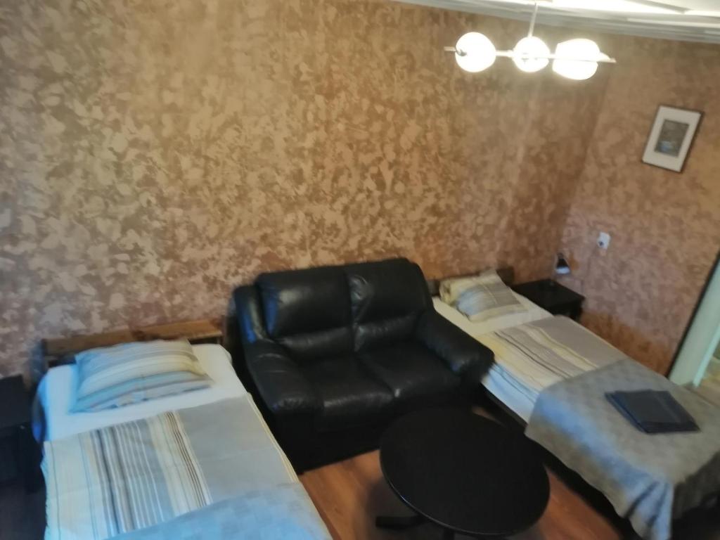 a room with two beds and a leather chair at Apartment by the park in Imatra