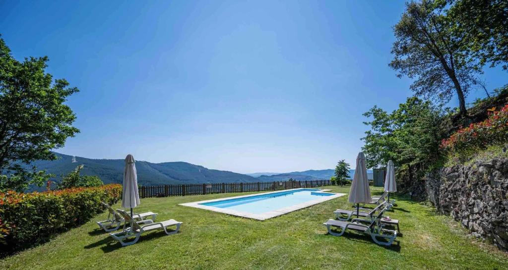 uma piscina com espreguiçadeiras e guarda-sóis em Quinta da Baldieira em Mondim de Basto