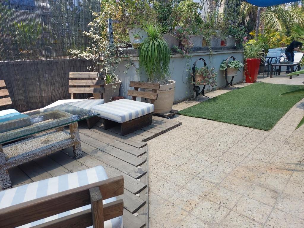 a patio with benches and a table and grass at Indigo roof garden Apt. 1BR 1BA in Tel Aviv