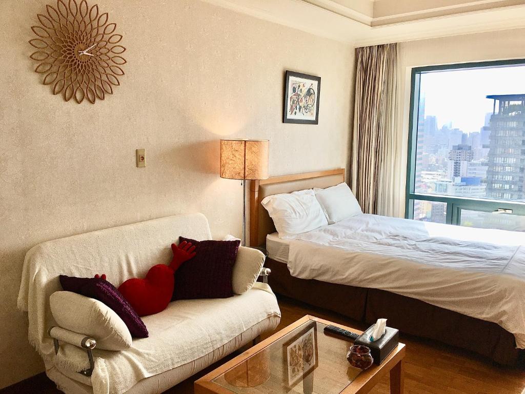 a hotel room with a bed and a couch and a window at 台中晶華居 Fine House Taichung in Taichung