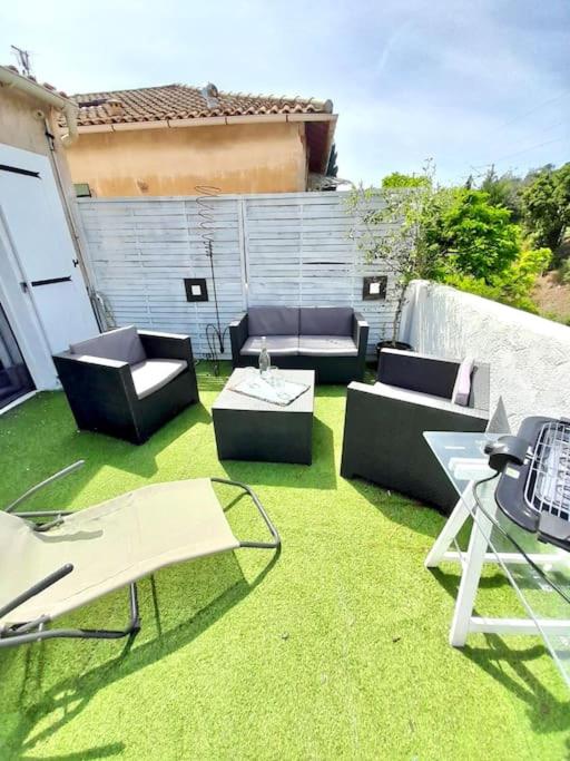 une terrasse avec des canapés et des chaises sur la pelouse dans l'établissement T3 haut de villa avec terrasse de 25m2, à Toulon
