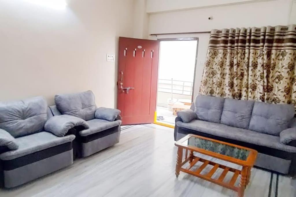 a living room with two couches and a red door at 2 BHK Fully Furnished in Kukatpally #201 in Hyderabad