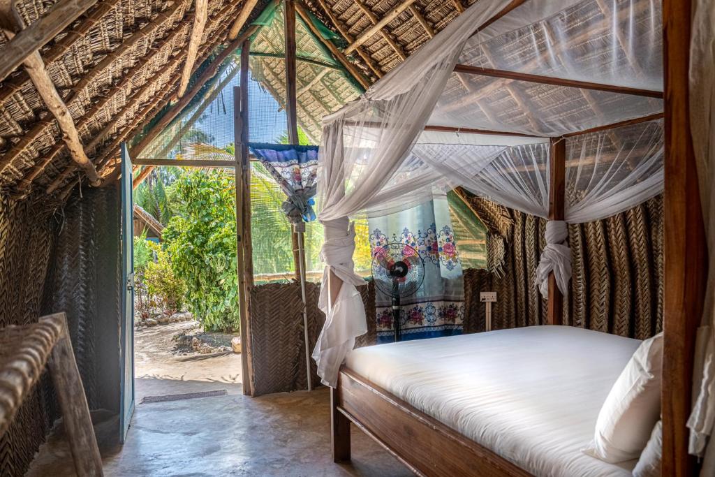 ein Schlafzimmer mit einem Himmelbett und einem Fenster in der Unterkunft Paje Beach Bandas in Paje