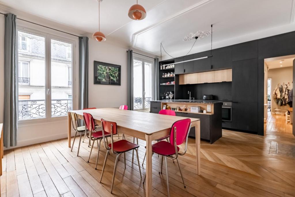 a kitchen and dining room with a wooden table and chairs at Veeve - Back to Black in Paris