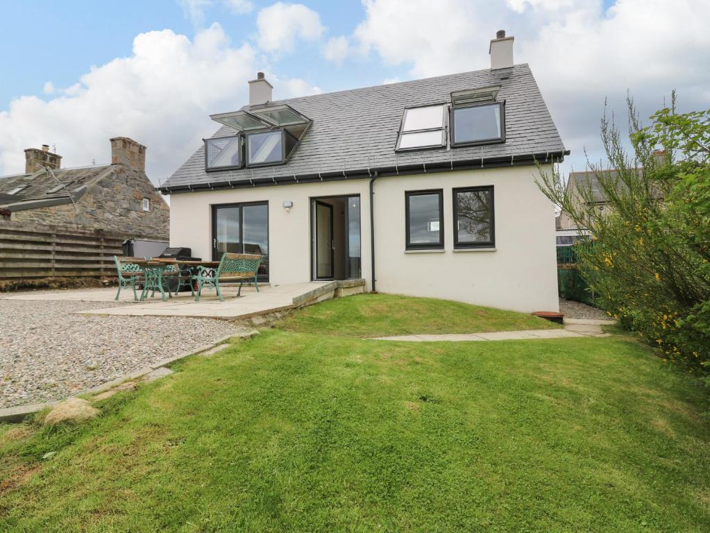 a white house with a patio and grass at Berg Cottage in Ballindalloch