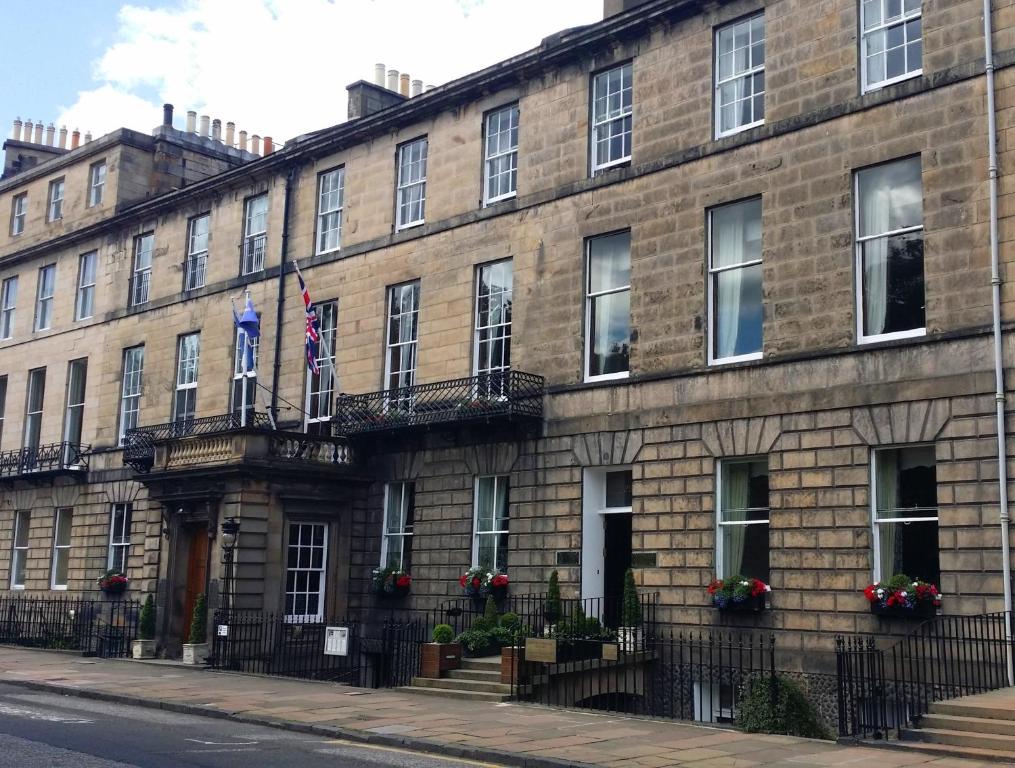 ein großes Backsteingebäude mit zwei Flaggen darauf in der Unterkunft Royal Scots Club in Edinburgh