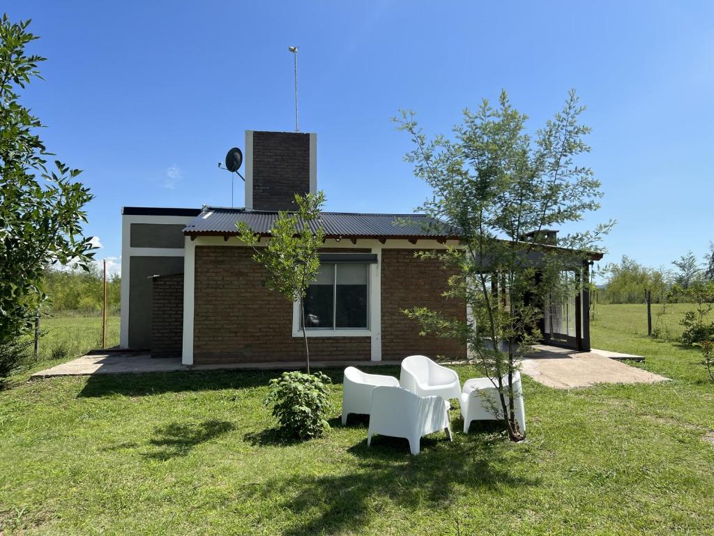 una casa con dos sillas blancas en un patio en El Retiro - Casa de campo en Los Reartes en Los Reartes