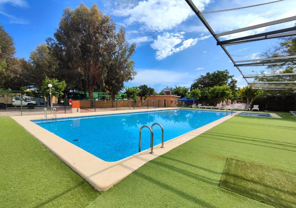 a swimming pool in a park with a grass field at Camping El Jardín in El Campello