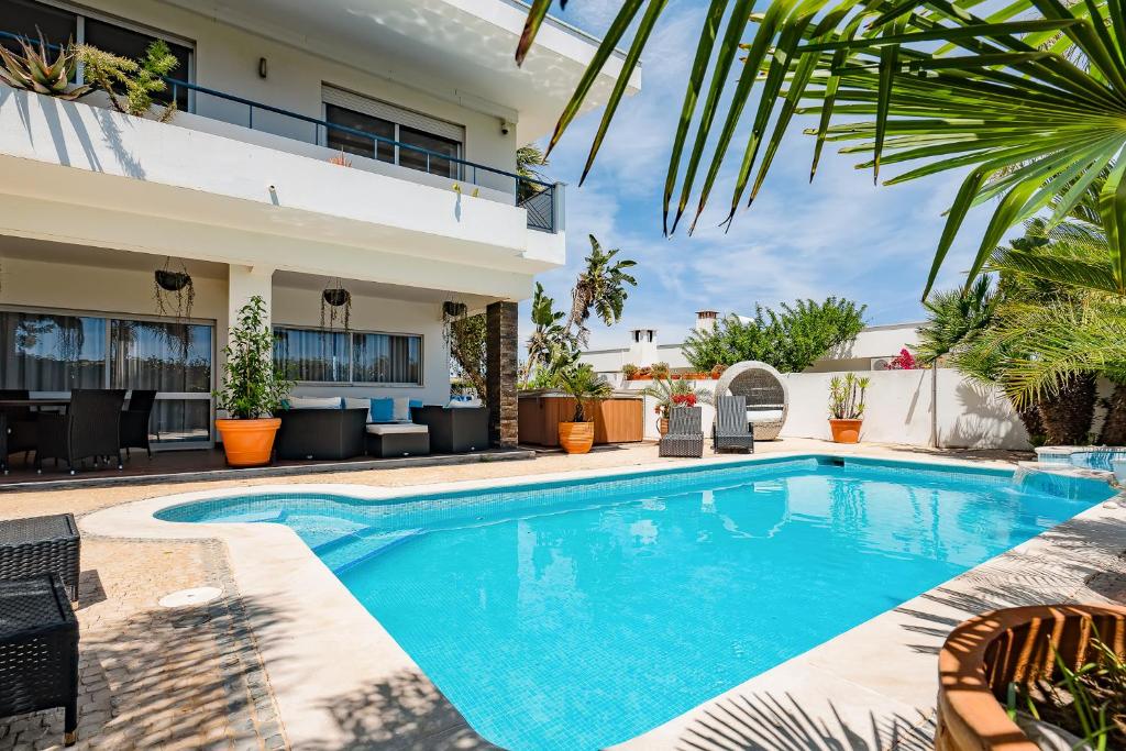 a swimming pool in front of a house at Deluxe 4BDR House W/ Pool by LovelyStay in Portimão