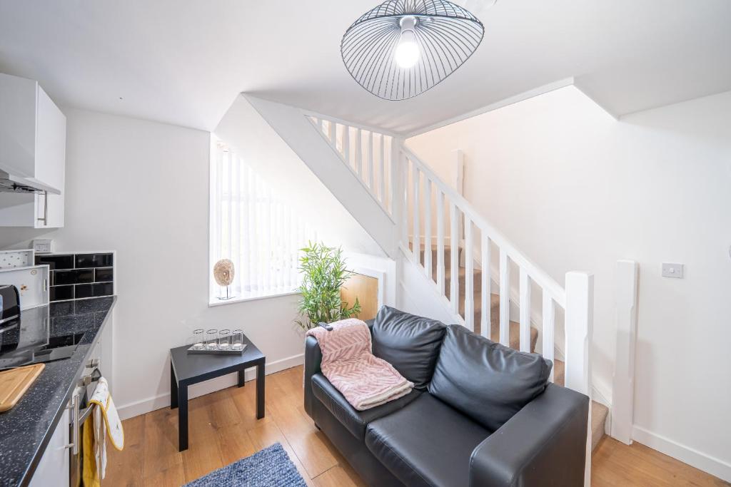 a living room with a black leather couch and stairs at Bv Kirkstall Central 1 Bedroom Apt Free Private Parking in Leeds