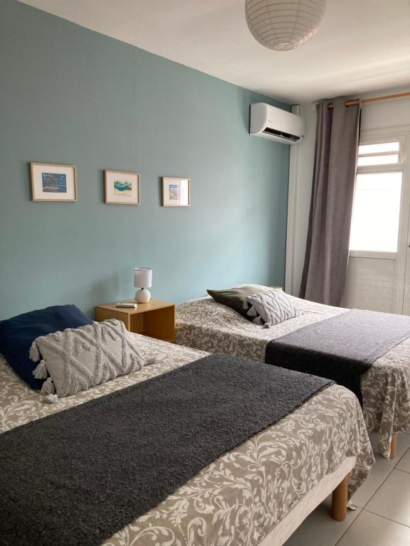 a bedroom with two beds and a window at Le Toutapied , Sainte-Anne, appartement en plein centre in Sainte-Anne