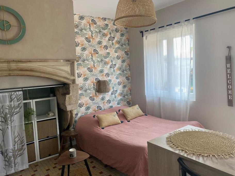 a bedroom with a pink bed and a fireplace at L’évidence…. in Flavigny-sur-Moselle