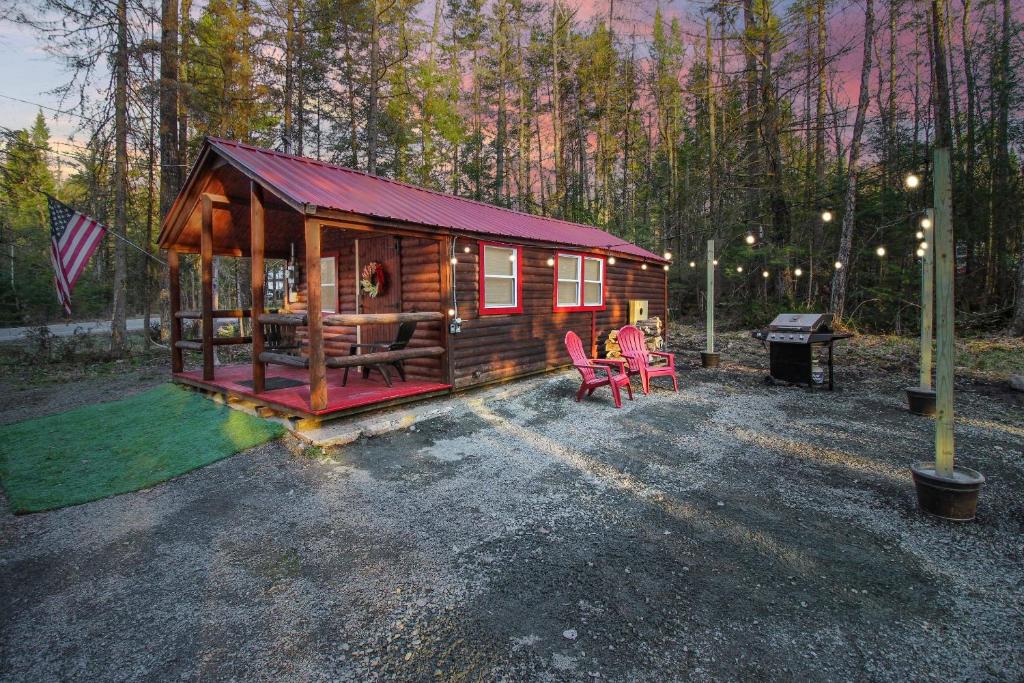 a cabin in the woods with two chairs and a grill at Travelers Haven in Whitefield