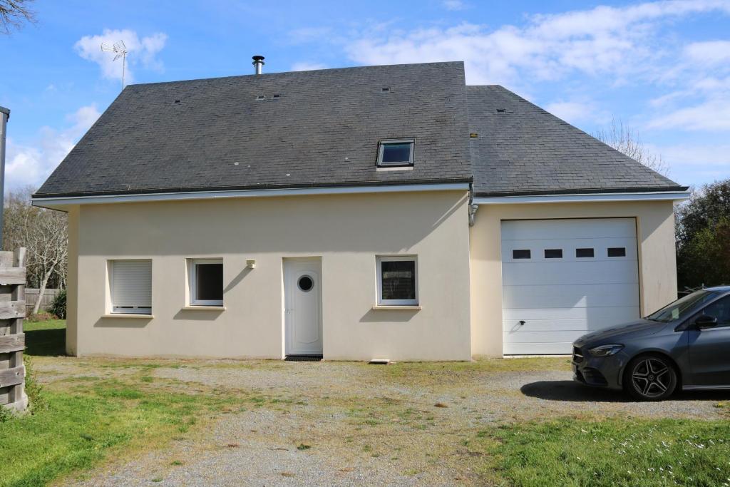 un garage blanc avec une voiture garée devant. dans l'établissement maison familiale, à La Turballe