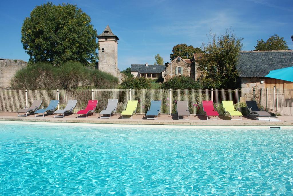 - une rangée de chaises à côté de la piscine dans l'établissement Le Chateau de Pervinquieres, à Ginals