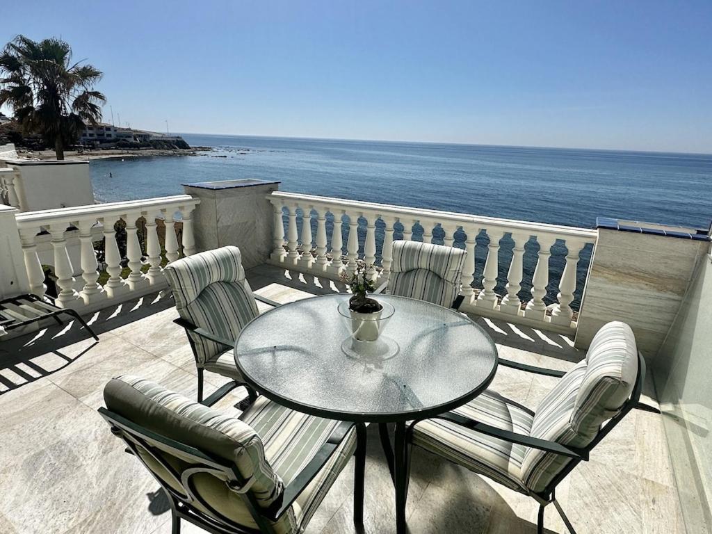 una mesa y sillas en un balcón con vistas al océano en Beachfront apartment with pleasant views of the sea and the historic lighthouse., en Mijas Costa