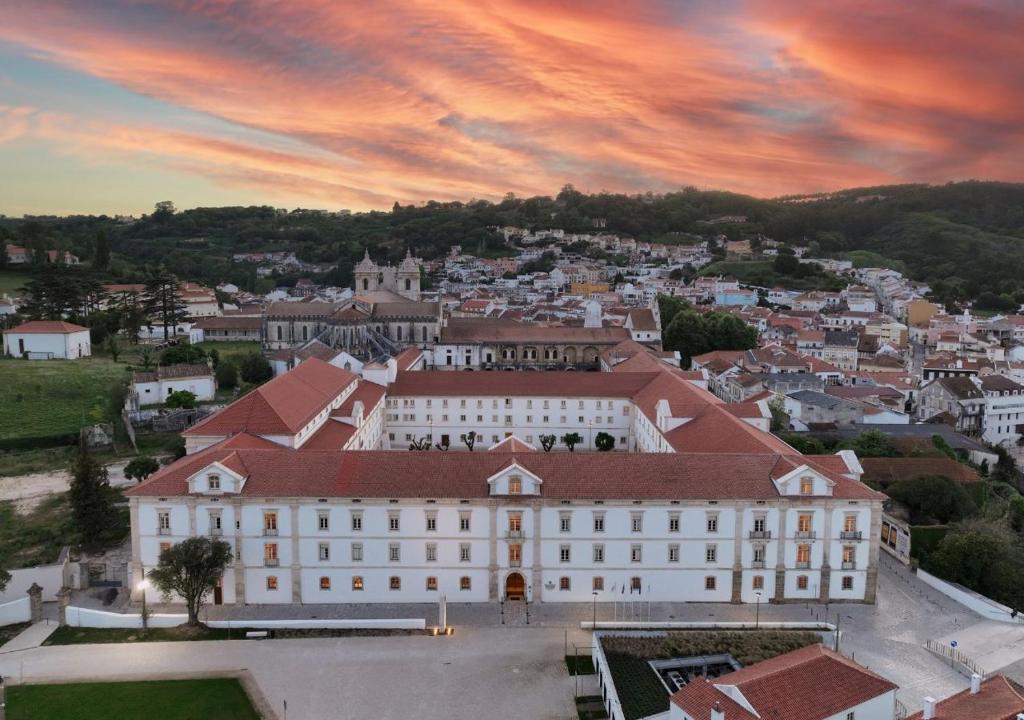 una vista aerea di un grande edificio bianco con una città di Montebelo Mosteiro de Alcobaça Historic Hotel ad Alcobaça