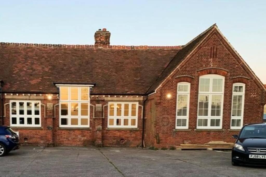 a brick house with white windows and a parking lot at Bodham School Halls - 5 Bedrooms in Bodham