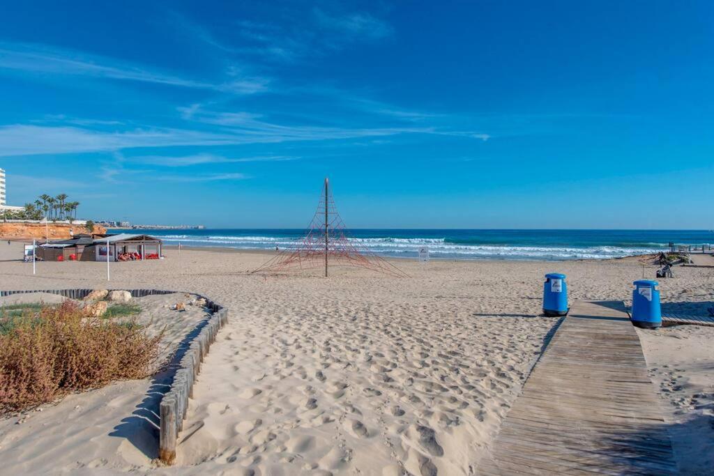 a sandy beach with two blue trash cans on it at HE sunny terrace t in Cabo Roig