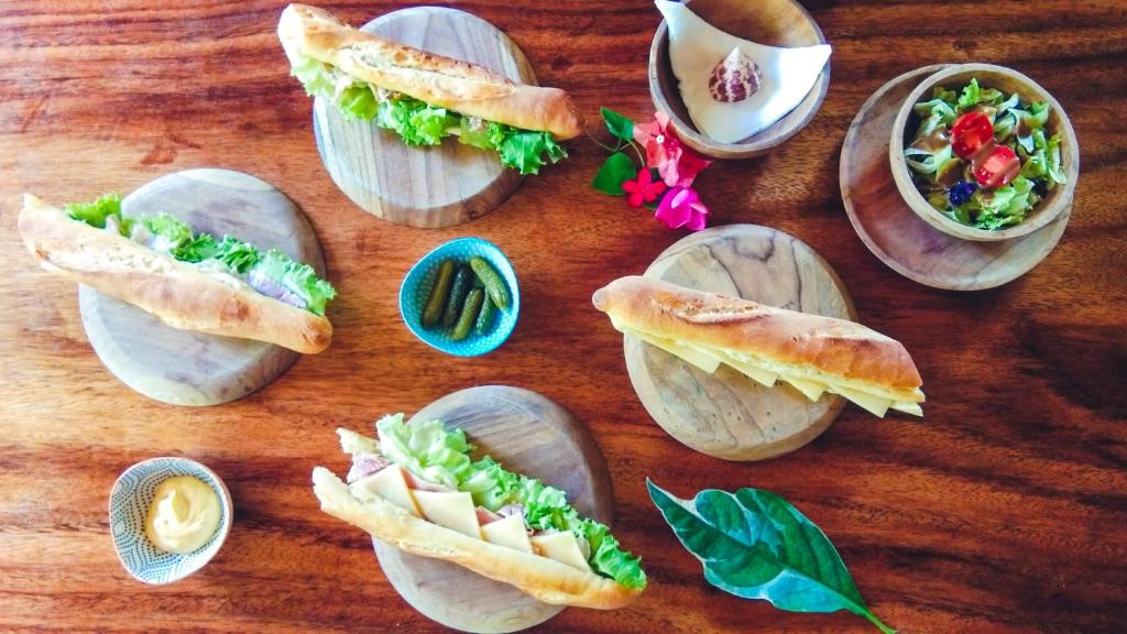 un grupo de sándwiches en platos en una mesa de madera en Café des Arts Gili Air, en Gili Air