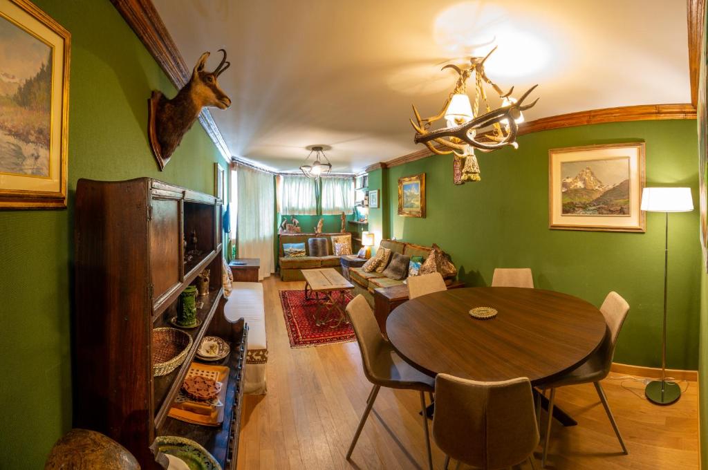 uma sala de jantar com paredes verdes e uma mesa e cadeiras em Maison 21 Cervinia cir n 0468 em Breuil-Cervinia