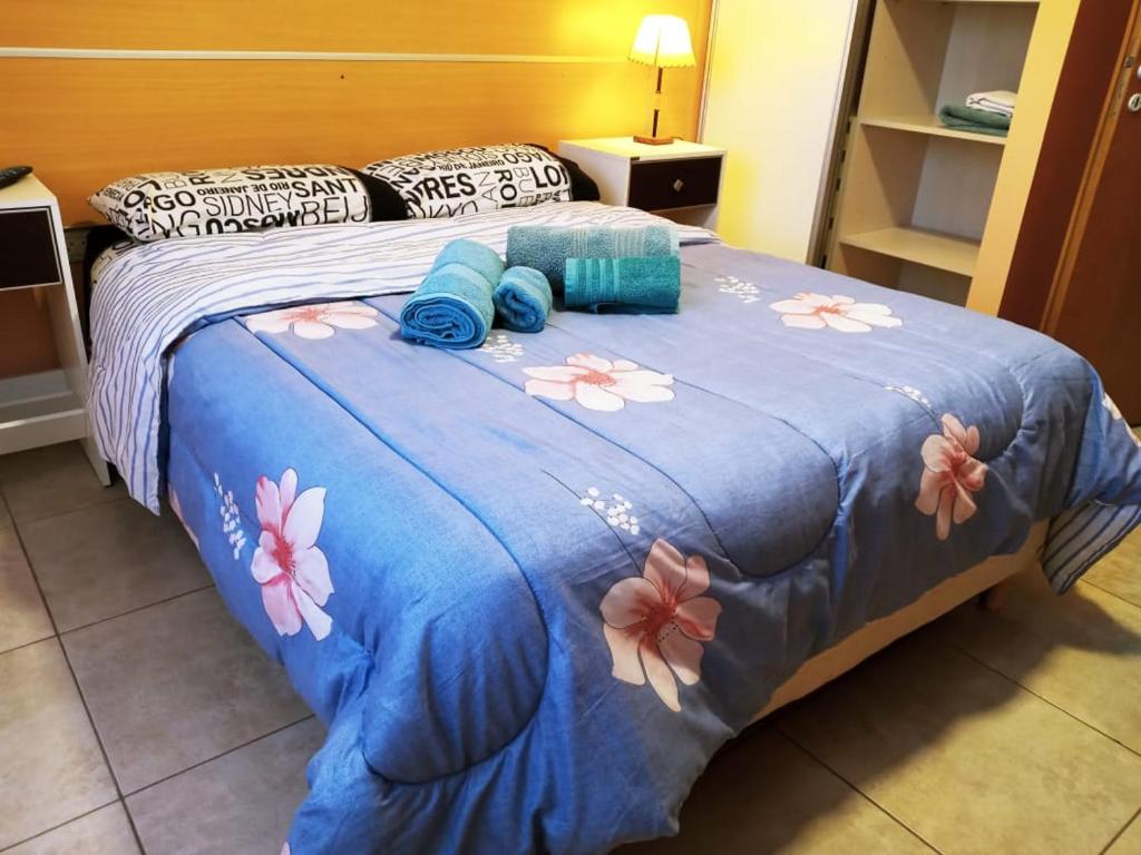 Una cama con una manta azul con flores. en Cálido departamento en Ushuaia en Ushuaia