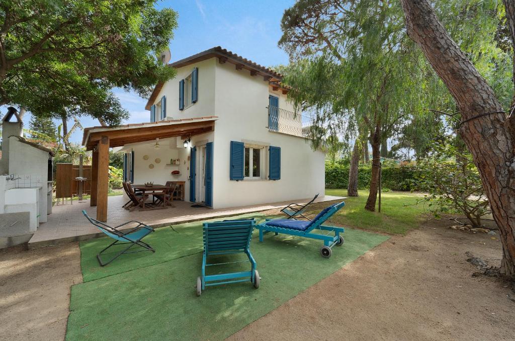 a house with blue chairs in the yard at Villa Montali in Santa Margherita di Pula