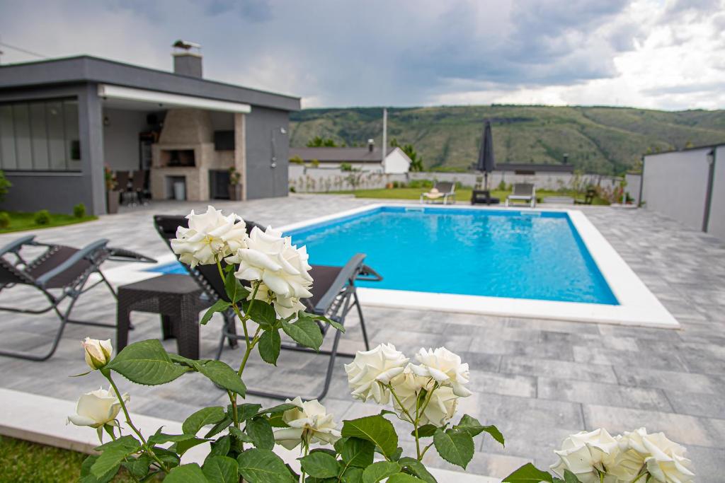 a swimming pool with white roses in front of a house at Villa Vukas in Mostar