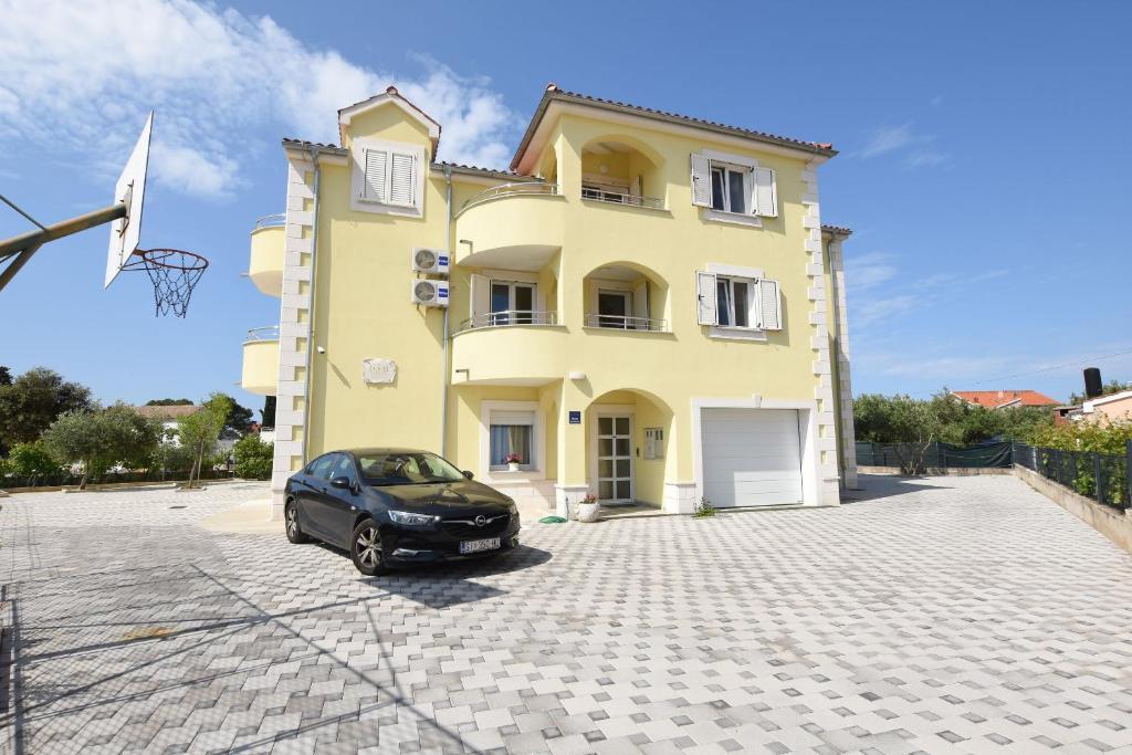a car parked in front of a yellow house at Apartments Mario in Brodarica