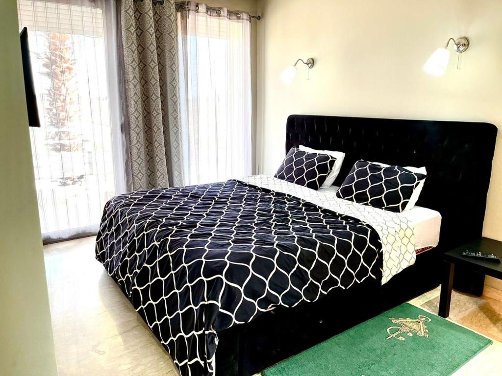 a black and white bed in a room with windows at Short Stay Apartment aéroport casablanca in Nouaseur