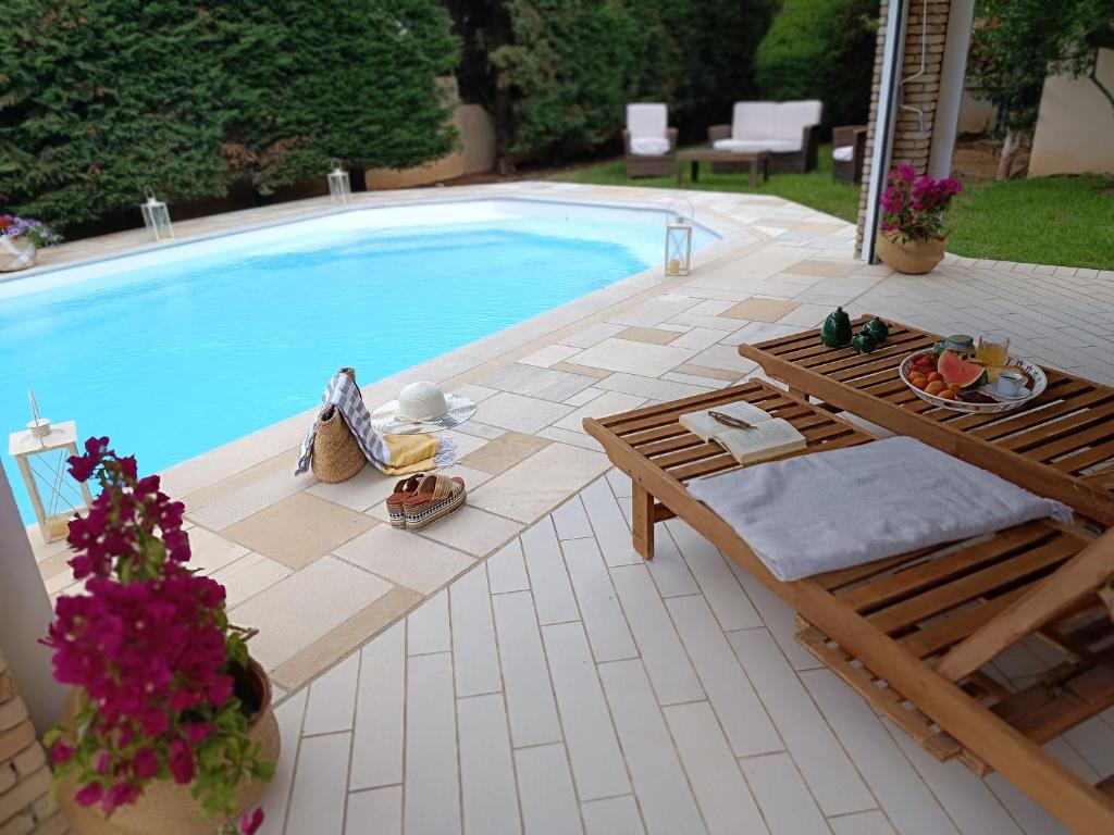 een zwembad met een tafel en een bank ernaast bij Celestial Azure Villa, your Athenian Country House Retreat in Markopoulon