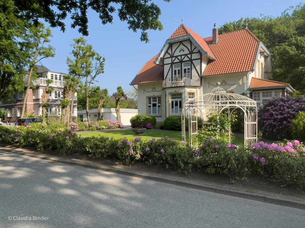 een huis met een tuinhuisje en bloemen bij Villa 1912 in Bad Zwischenahn