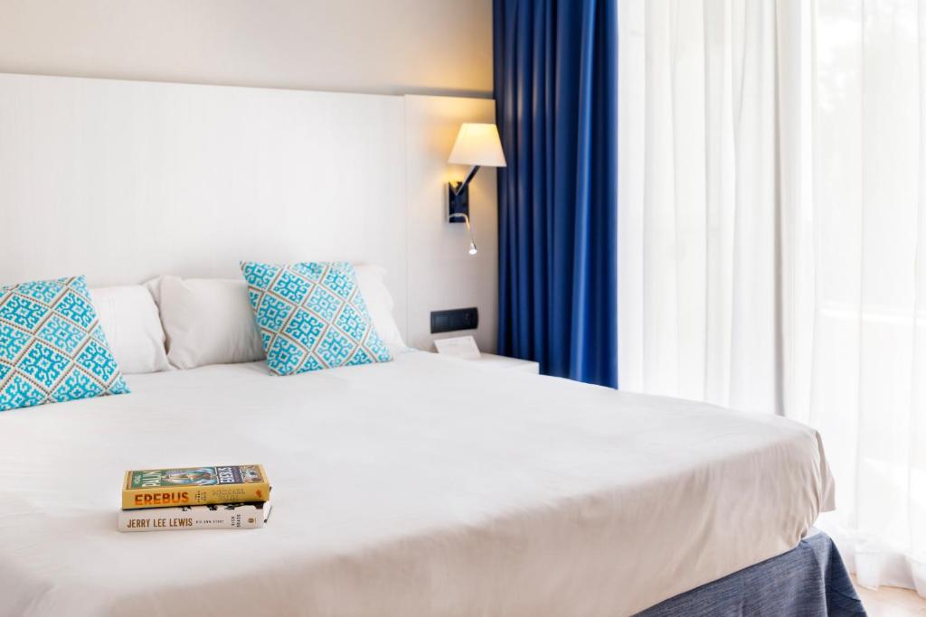 a hotel room with a bed with a book on it at Mar Hotels Alcanada in Port d'Alcudia