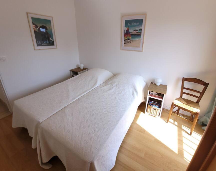 a bedroom with a white bed and a chair at Bien-être &amp; Panorama - Les Gîtes de la Côte d&#39;Amour in Le Croisic
