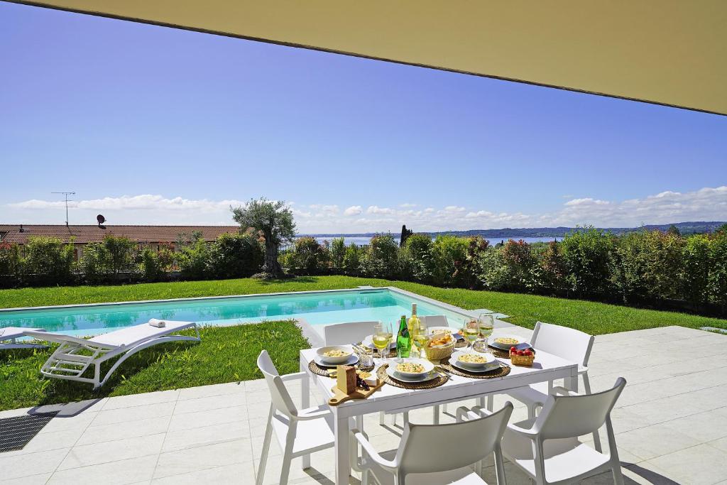 una mesa con comida y bebidas junto a una piscina en Villa Ester by Wonderful Italy en Moniga