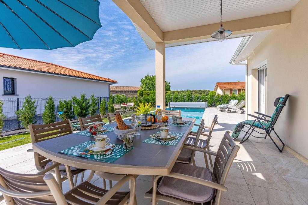 a patio with a table with chairs and an umbrella at Villa du Lac in Gastes