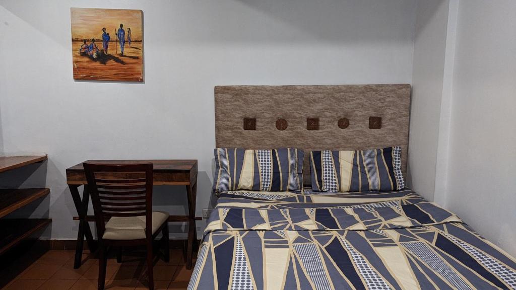 1 dormitorio con 1 cama y 1 mesa con silla en A lovely studio apartment with gym and pool access en Dar es Salaam