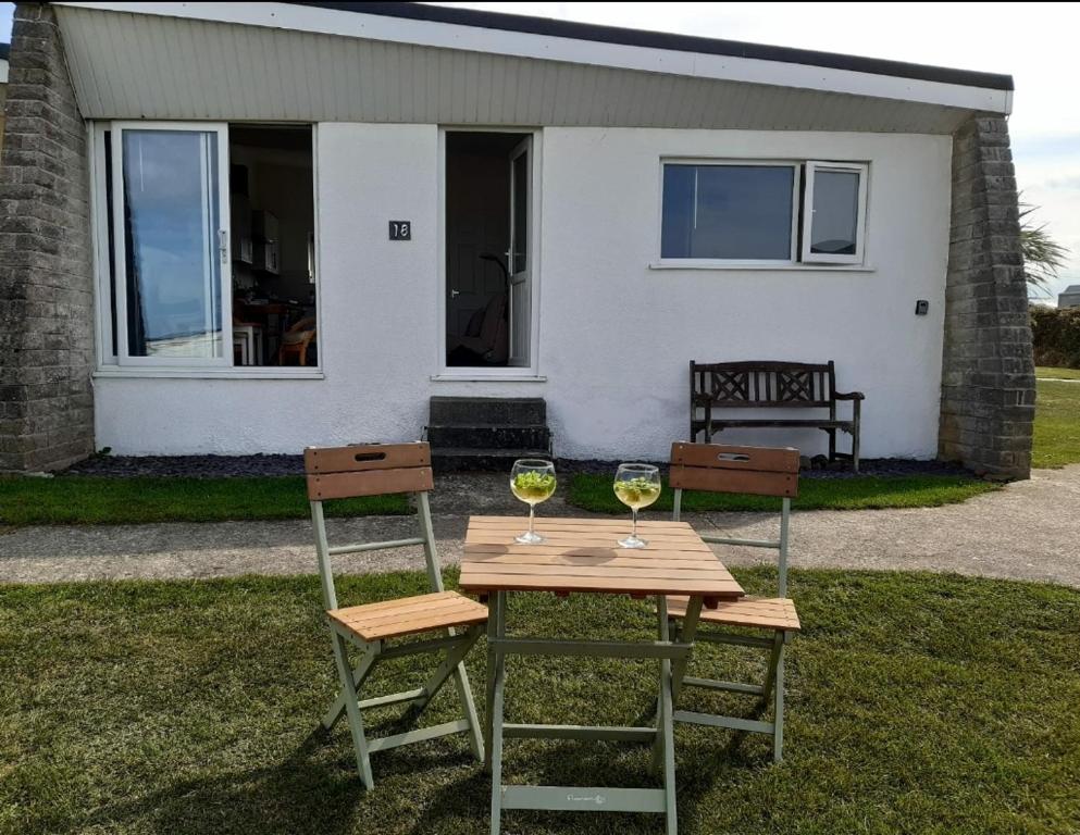 two glasses of wine sitting on a table in front of a house at Chalet 18 Widemouth Bay Holiday Village in Bude