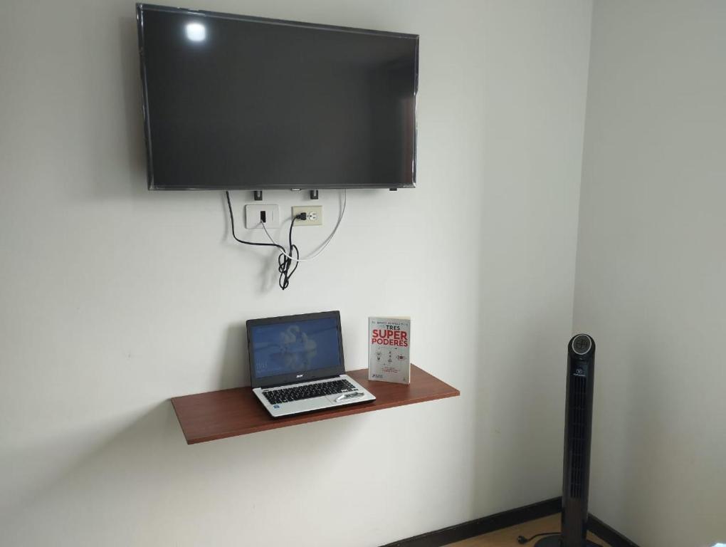 a laptop sitting on a shelf with a tv on a wall at Cómoda habitación en apartamento in Medellín