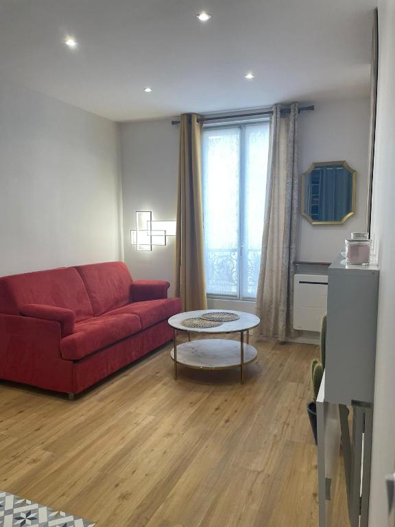un salon avec un canapé rouge et une table dans l'établissement Montmartre Cosy, à Paris