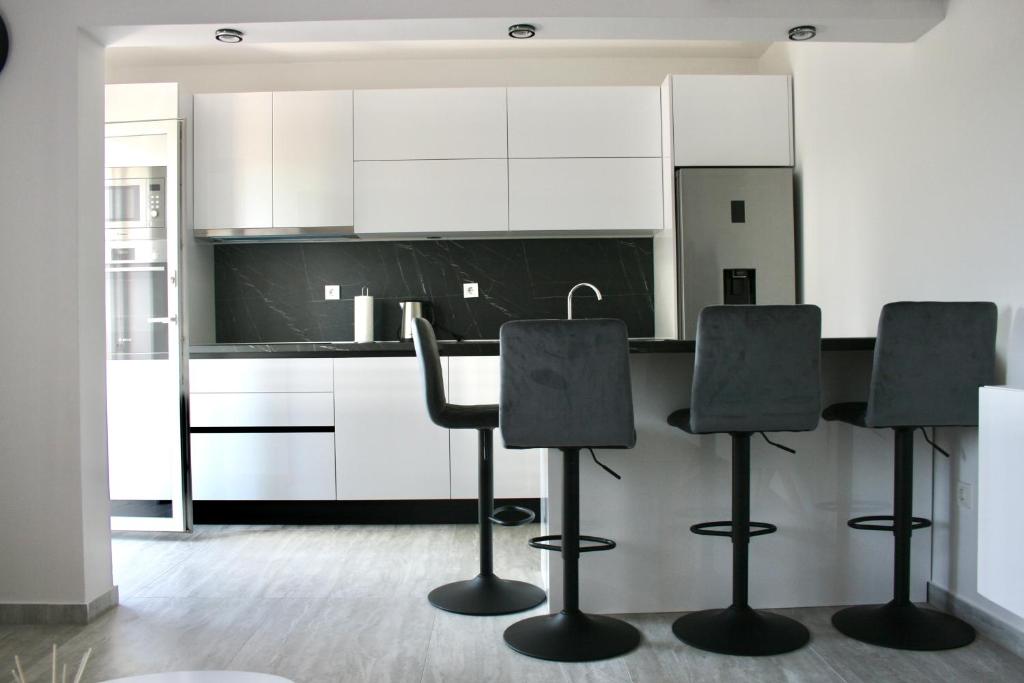 a kitchen with white cabinets and black bar stools at Apartments Antea in Trogir