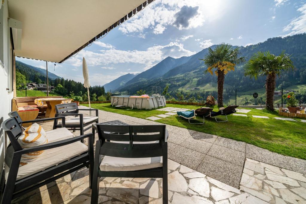 d'une terrasse avec une table et des chaises et des montagnes en arrière-plan. dans l'établissement Haus Reimon Apt Monika, à San Leonardo in Passiria