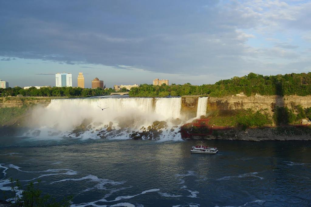 a boat in front of a waterfall on a river at Pelican guest house. Village style living. Spend vacation time in Eco place! in Fort Erie