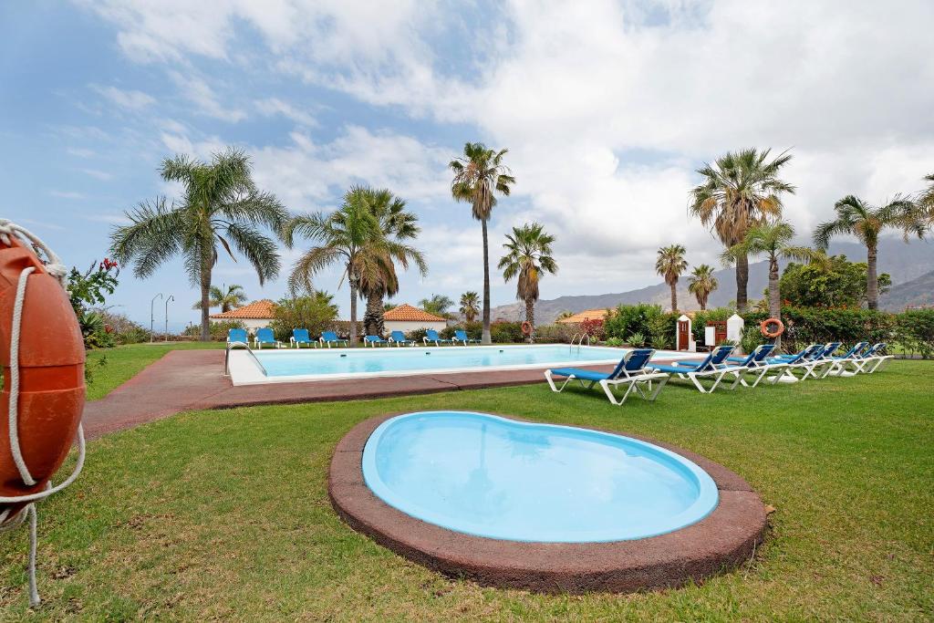 La Villa La Palma- 2 dormitorios A في Los Barros: مسبح كبير مع كراسي الصالة والنخيل