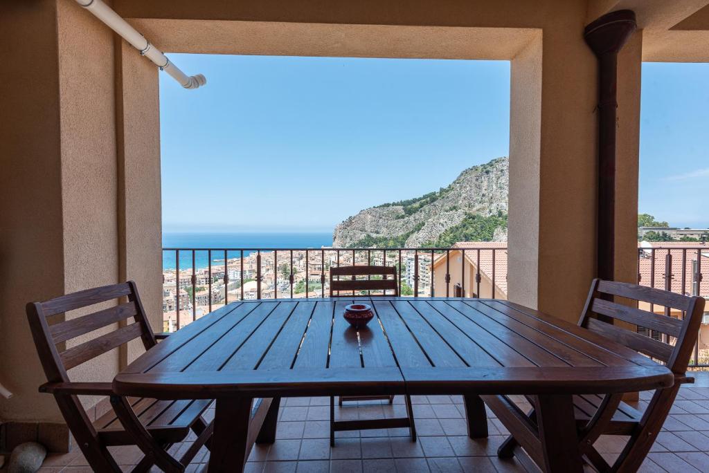 a wooden table on a balcony with a view of the ocean at Moderno Appartamento in Cefalù