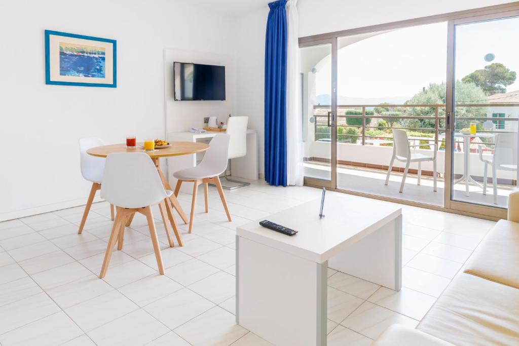 a living room with a table and chairs and a large window at Mar Hotels Alcanada in Port d'Alcudia