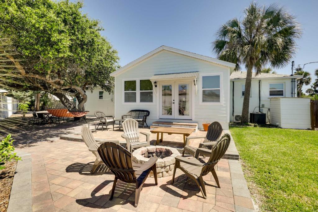 a patio with chairs and a table in front of a house at Chic Coastal Cottage with Fire Pit Walk to Pier! in Saint Augustine Beach