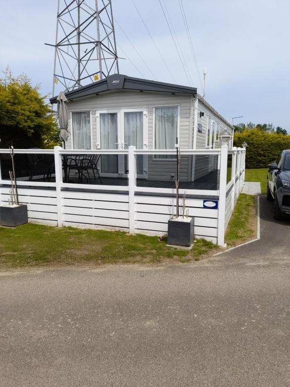 a white house with a white fence and a car at Kent Getaways in Westgate-on-Sea